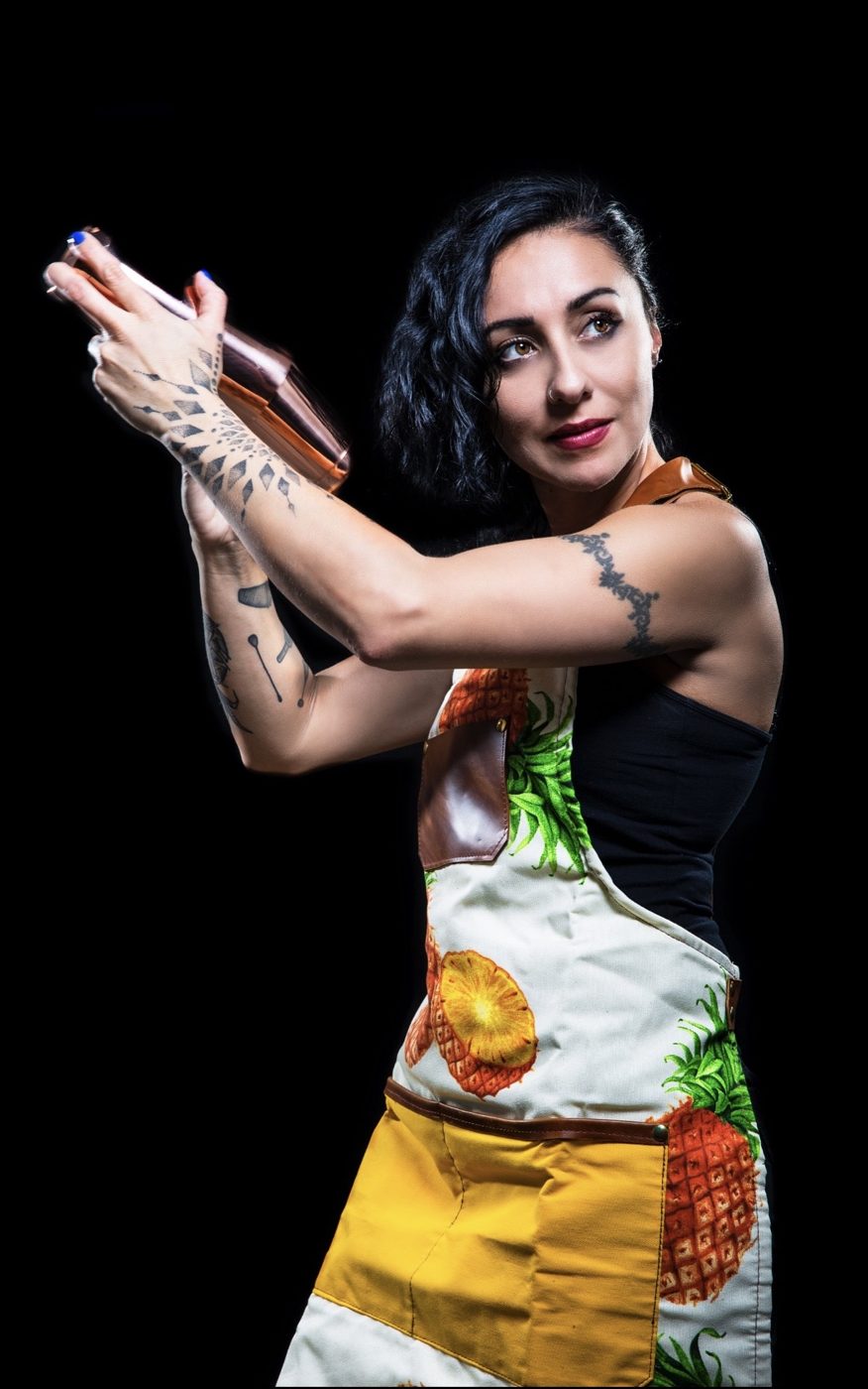 Portrait of a bartender with tattoos shaking a cocktail